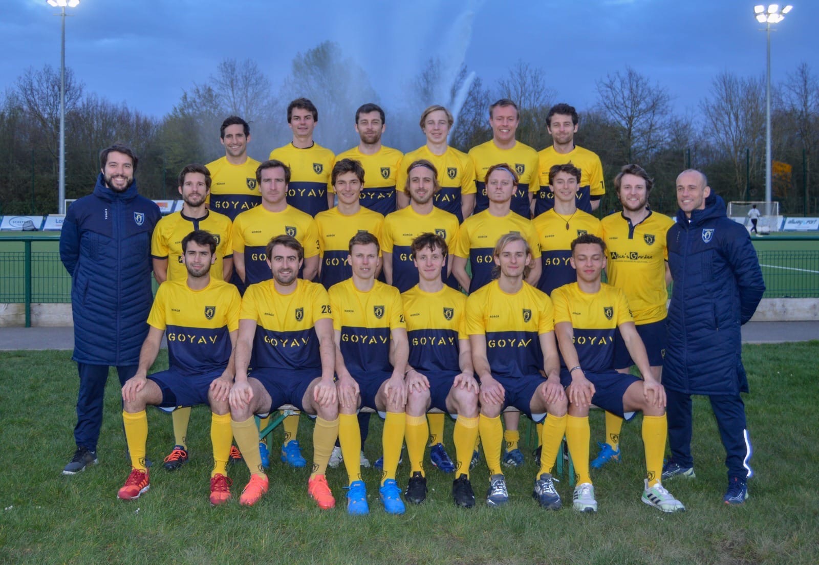L'équipe 1 Hommes en maillots jaunes, posant sur le terrain à la tombée du jour.